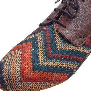 Puede incluir: Zapatos marrones de cuero con cordones y una puntera de tela con estampado geom&eacute;trico de colores.