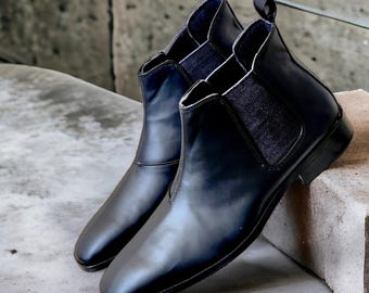 May include: A pair of black leather Chelsea boots with elastic side panels. The boots have a pointed toe and a low heel.