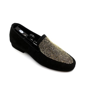 May include: Black suede loafers with a gold beaded design on the toe.