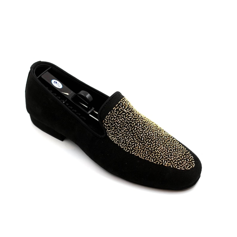 May include: Black suede loafers with a gold beaded design on the toe.