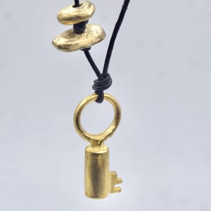 Pendant in the shape of an old key on a leather strap with designed elements