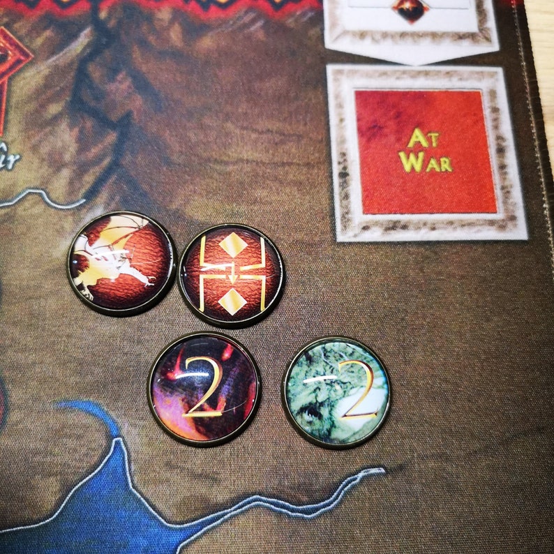 Puede incluir: Cuatro fichas de juego redondas. Una ficha es roja con un drag&oacute;n dorado, otra es roja con un escudo dorado, otra es roja con un n&uacute;mero 2 dorado y la &uacute;ltima es verde con un n&uacute;mero 2 dorado.