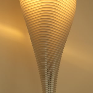 May include: A modern, white, layered pendant light fixture. The design features numerous horizontal, curved slats that create a spiraling, cone-like shape. The light emits a warm, inviting glow, suggesting a contemporary home decor element.