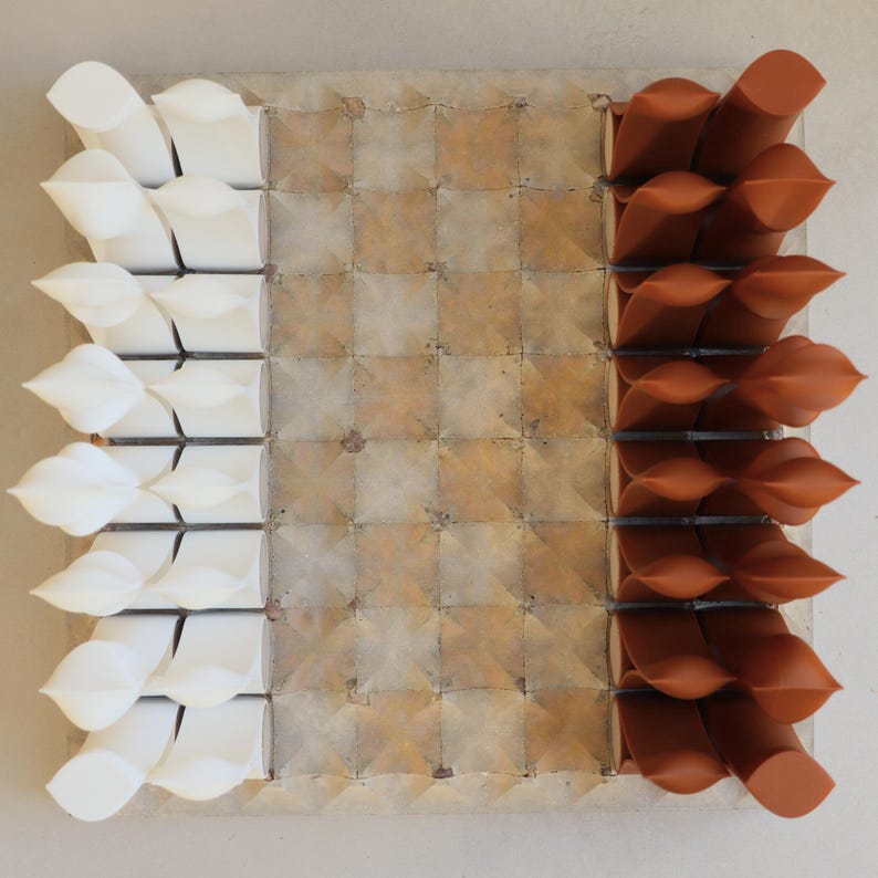 Op de afbeelding: Abstract vierkant kunstwerk met een rasterpatroon. De linkerkant heeft witte, bladachtige vormen, terwijl de rechterkant bruine, gedraaide vormen heeft. Het midden heeft een getextureerd, vierkant patroon in bruin- en beigetinten.