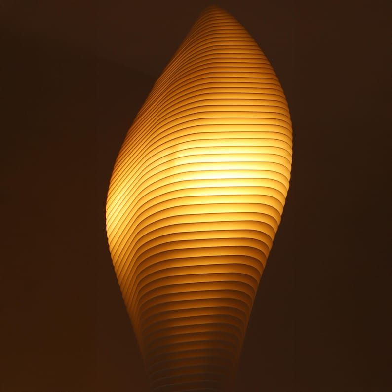 May include: A modern, abstract lamp with a warm, yellow glow. The lamp's design features a series of horizontal, curved lines that create a layered effect. The lamp's shape is reminiscent of a flame or a stylized leaf.