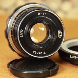 Op de afbeelding: Een zwart en zilveren camera lens met de tekst "28/52", "7125568", "И-61" en "CCCP" erop gedrukt.