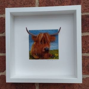 A needlefelted picture of a highland cow