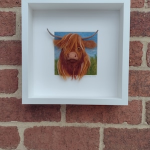 A needlefelted picture of a highland cow