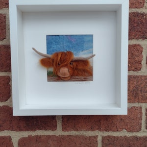 A needlefelted picture of a highland cow