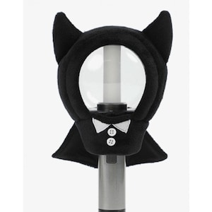 May include: A black plush light stick cover shaped like a bat, with pointed ears and a cape. The cover has a white bow tie and two white buttons. The light stick is silver and has a clear, round cover.