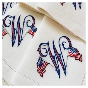 May include: White linen napkins with blue and red embroidered monograms and American flags.