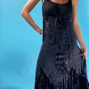 May include: A black velvet maxi dress with a lace overlay and beaded embellishments. The dress has a scoop neck and a tie at the waist.