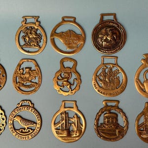 Peut inclure: Une collection de quatorze plaques de harnais en laiton circulaires présentant divers motifs en relief, notamment des monuments historiques, des animaux et des navires. Chaque pièce possède une petite boucle supérieure pour la fixation.