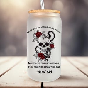 May include: A white ceramic mug with a black handle and the text "But First, Coffee" in a bold, black font. The mug is set against a neutral background, highlighting its simple design.