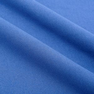 May include: Close-up of a textured, bright blue fabric with diagonal folds. The fabric has a subtle woven pattern, creating a sense of depth and texture. The color is a vibrant, solid blue, suitable for apparel or home decor.