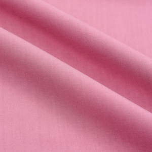 May include: A smooth, soft, pink fabric with a subtle sheen. The fabric is folded in a gentle curve, creating a soft, flowing texture.