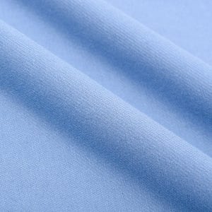 May include: Close-up of light blue fabric with soft folds. The fabric has a smooth texture and a subtle sheen, creating a sense of depth and movement. The color is a pale, calming blue, suitable for various textile applications.