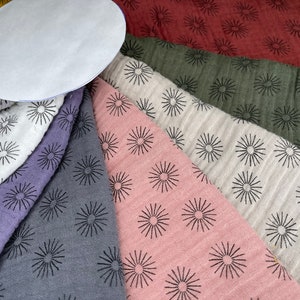 May include: A collection of fabric swatches with a black sunburst pattern on a variety of colors, including red, green, white, pink, gray, and purple.