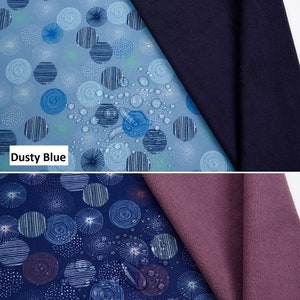 May include: Two swatches of soft shell fabric with a digital print of circles. The top swatch is dusty blue with a navy blue backing. The bottom swatch is navy blue with a mauve backing. The fabric is water repellent, breathable, and has a TPU layer bonded to it.