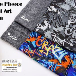 May include: Three pieces of fleece fabric with a graffiti art pattern. The fabric is in shades of gray, blue, orange, and black. The fabric is labeled "Khaki" and "Purple". The fabric is certified by Oeko-Tex Standard 100.