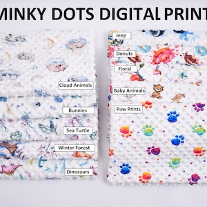 Op de afbeelding: Een stapel witte minky dot digitale print stofstalen. Ontwerpen zijn onder meer "Cloud Animals", "Bunnies", "Sea Turtle", "Winter Forest", "Dinosaurs", "Jeep", "Donuts", "Floral", "Baby Animals" en "Paw Prints". De tekst "MINKY DOTS DIGITAL PRINT" staat bovenaan.