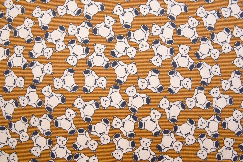 May include: A brown fabric with a repeating pattern of white teddy bears wearing bow ties. The bears are facing different directions and are arranged in a random pattern.