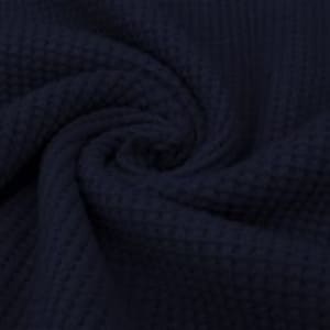 May include: Close-up of navy blue waffle knit fabric, showing a textured pattern. The fabric is swirled, creating a spiral effect. The material appears soft and pliable, with a subtle sheen.