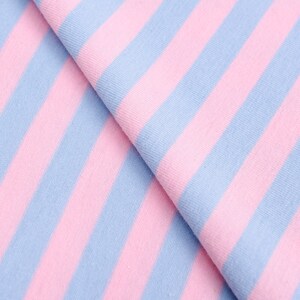 May include: Pink and light blue striped fabric. The fabric is folded in half, showing the stripes running diagonally.