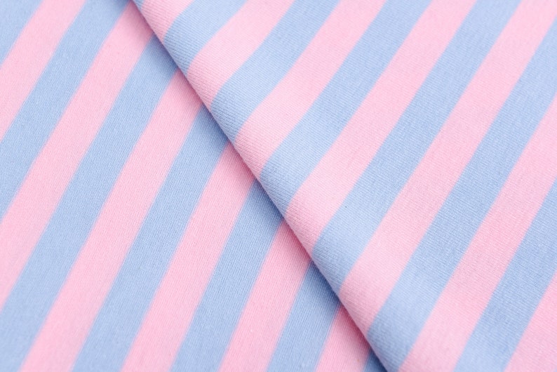 May include: Pink and light blue striped fabric. The fabric is folded in half, showing the stripes running diagonally.