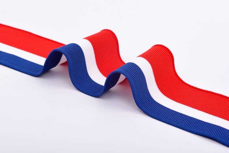 May include: A wavy ribbon with a tricolor design of red, white, and blue. The ribbon has a ribbed texture and is displayed against a white background. The colors are vibrant and distinct.
