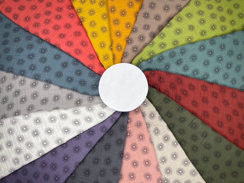 May include: A collection of 12 fabric swatches with a repeating pattern of black sunbursts on a variety of colored backgrounds, including red, yellow, green, blue, gray, and pink.