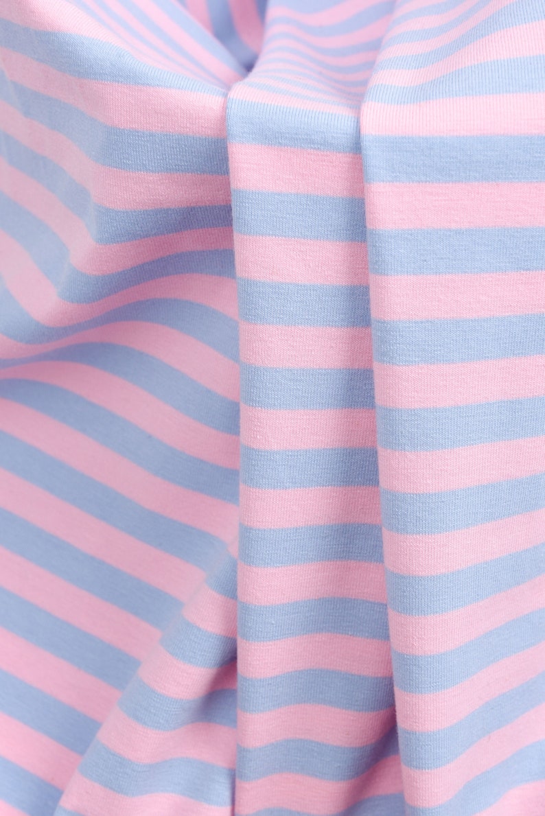 May include: Close-up of pink and blue striped fabric. The fabric is folded and wrinkled, showing the texture of the material.