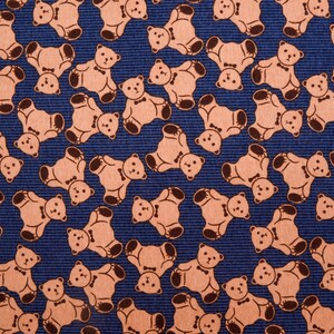May include: A blue fabric with a repeating pattern of brown teddy bears wearing bow ties. The bears are facing different directions and are arranged in a staggered pattern.