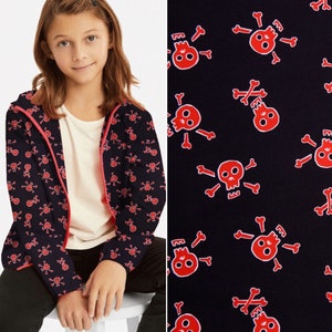 May include: A black zip-up jacket with a red skull and crossbones pattern. The jacket has a pink zipper and a hood.