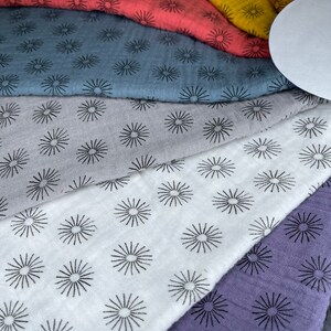 May include: A set of six fabric squares with a repeating pattern of black starbursts on a variety of colors, including gray, white, purple, and blue.