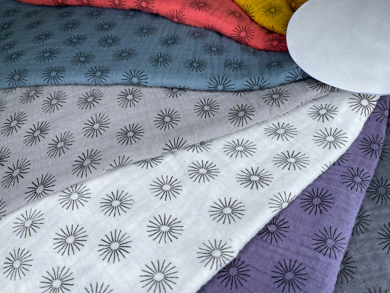 May include: A set of six fabric squares with a repeating pattern of black starbursts on a variety of colors, including gray, white, purple, and blue.