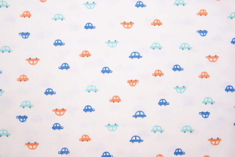 Op de afbeelding: Witte stof met een herhalend patroon van blauwe, oranje en lichtblauwe auto's. De auto's zijn allemaal in dezelfde richting gericht en hebben een eenvoudig, cartoonachtig ontwerp.