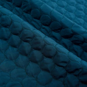 Puede incluir: Tela acolchada de color turquesa con un patr&oacute;n repetitivo de peque&ntilde;os c&iacute;rculos.