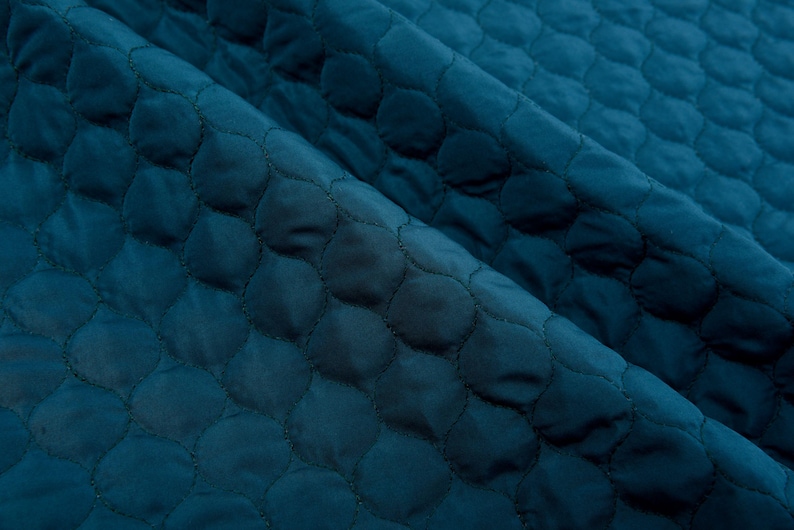 Puede incluir: Tela acolchada de color turquesa con un patr&oacute;n repetitivo de peque&ntilde;os c&iacute;rculos.