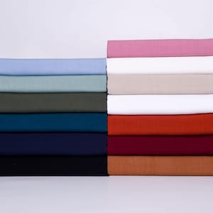 May include: A stack of fabric swatches in various colors, including light blue, green, teal, navy blue, black, pink, white, orange, red, and brown.