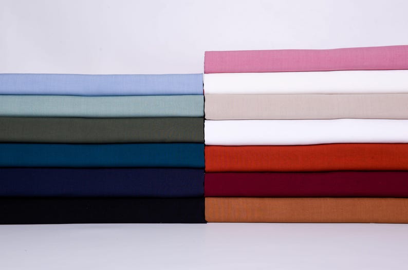 May include: A stack of fabric swatches in various colors, including light blue, green, teal, navy blue, black, pink, white, orange, red, and brown.