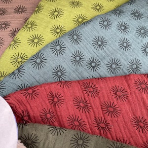 May include: A collection of fabric swatches with a repeating pattern of black starbursts on different colored backgrounds. The colors include brown, green, blue, red, and a light brown.