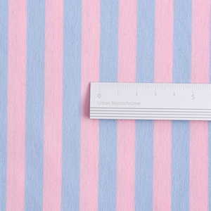 May include: A close-up of a pink and light blue striped fabric with a ruler measuring 8 inches long.