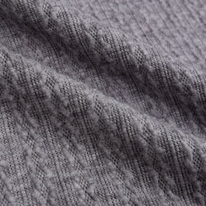 May include: Close-up of a gray knitted fabric with a textured pattern.