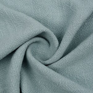 May include: A close-up of a soft, blue fabric with a textured weave. The fabric is folded and draped, showing its texture and drape.