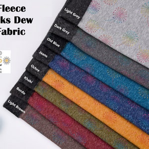 Könnte beinhalten: Eine Vielzahl von Farben aus weichem, flauschigem Fleece-Stoff mit einem Feuerwerksdesign. Der Stoff ist mit den Farben gekennzeichnet: Hellgrau, Dunkelgrau, Altblau, Jeans, Ocker, Khaki, Bordeaux und Hellbraun. Der Stoff ist Oeko-Tex Standard 100 zertifiziert.