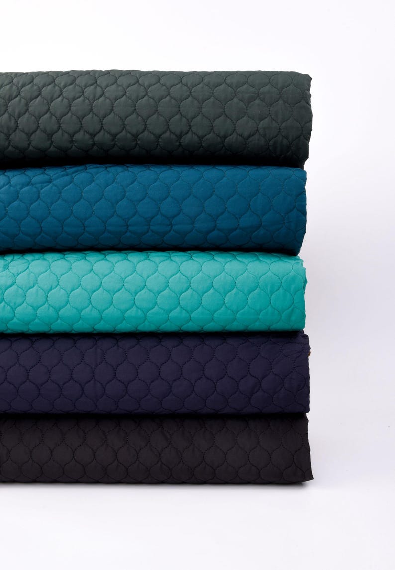 Puede incluir: Cinco rollos de tela acolchada en diferentes colores: verde oscuro, azul verdoso, turquesa, azul marino y negro. La tela tiene un patr&oacute;n de diamante.