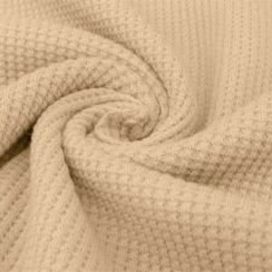 May include: Close-up of a beige waffle-knit fabric, tightly swirled to show texture. The fabric has a repeating grid pattern, creating a textured surface. The neutral color and detailed weave suggest a cozy textile.