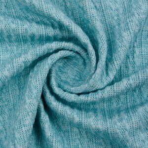 May include: A close-up of a teal blue knitted fabric with a textured pattern. The fabric is folded and twisted, creating a swirling effect.