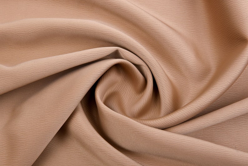 Puede incluir: Primer plano de una tela color beige con una superficie texturizada. La tela est&aacute; drapeada y arremolinada, creando pliegues y sombras suaves. El color es un tono c&aacute;lido y neutro, adecuado para diversos proyectos de costura y artesan&iacute;a.